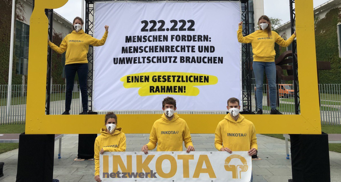 INKOTA-Mitarbeitende stehen mit einem großen Forderungs-Banner vor dem Kanzleramt in Berlin