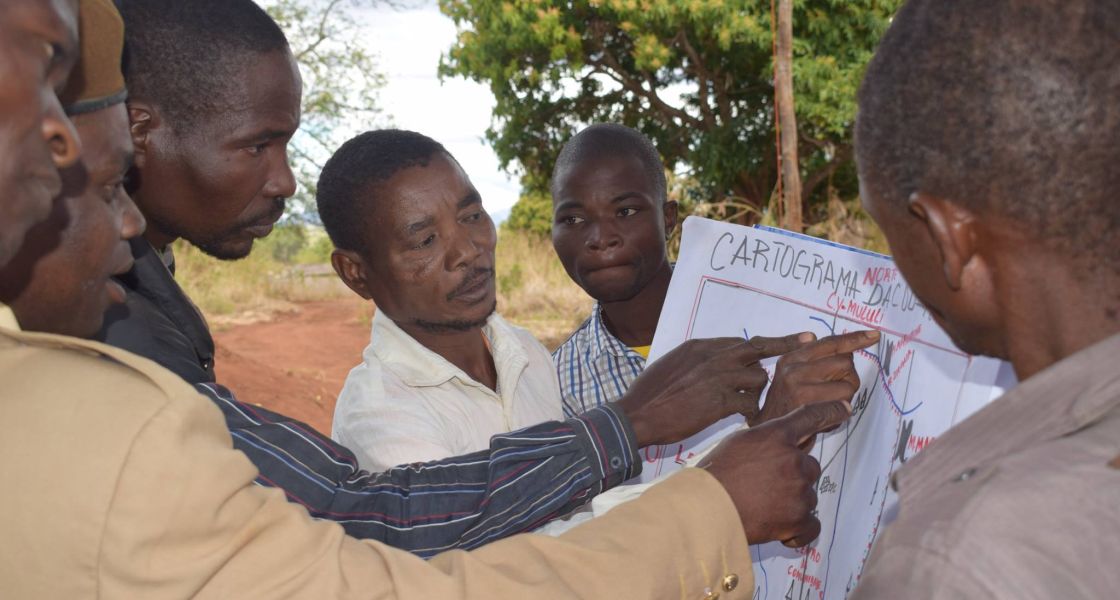Gruppe Männer zeigen mit den Händen auf eine Karte