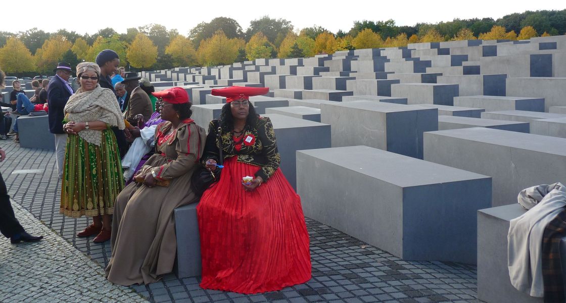 Frauen aus Namibia sitzen auf Stenen am Holocaust-Mahnmal in Berlin