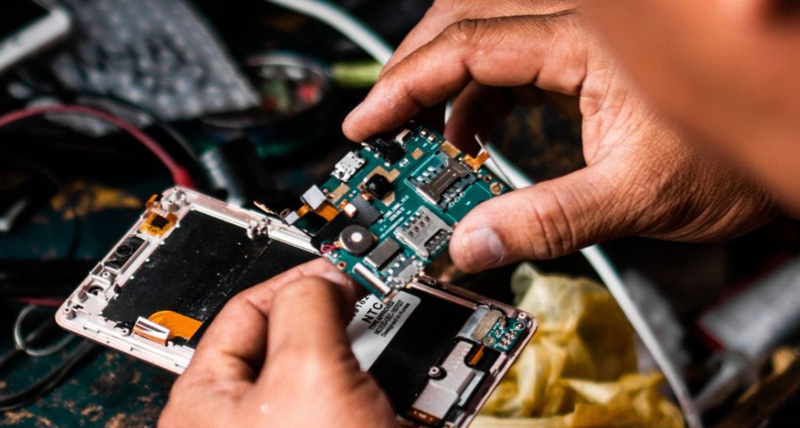 Ein Mann schaut eine Elektronikplatte, die er aus einem Handy herausgenommen hat