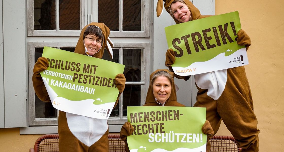 Drei Frauen in Osterhasenkostümen demonstrieren mit Plakaten