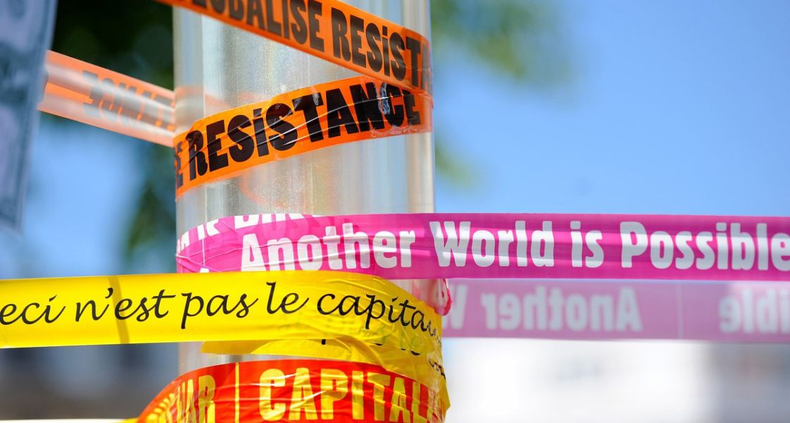 bunte Protestslogans auf Plastikbändern um einen Mast gewickelt