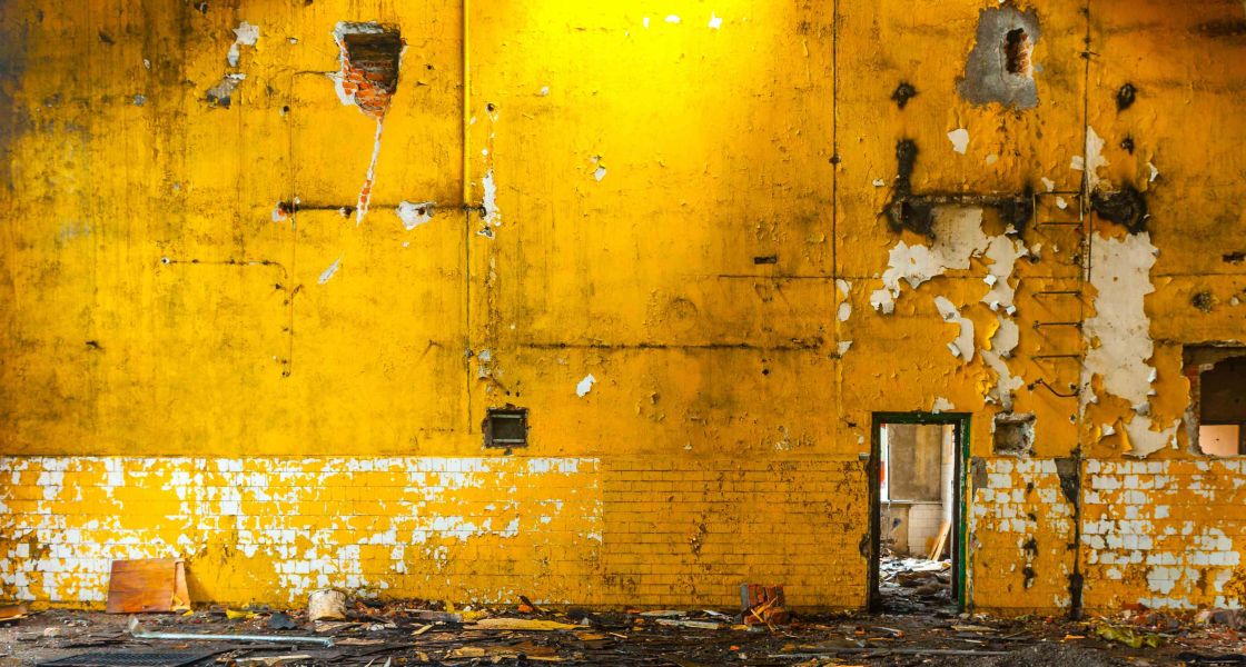 alte gelbe Fabrikwand, von der die Farbe abblättert