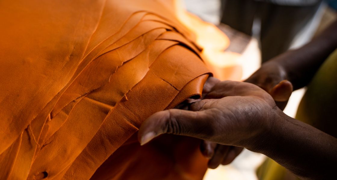 Hände halten einen Stapel orangefarbenen Leder