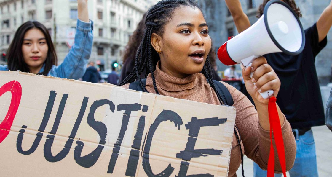 Eine Frau mit Megafon und Protestschild auf der Straße mit anderen zusammen