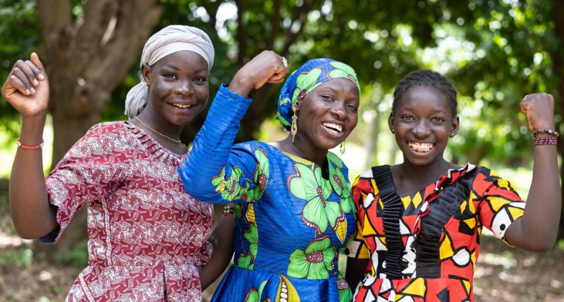 Drei Frauen stehen zusammen und halten je eine Faust hoch und lachen