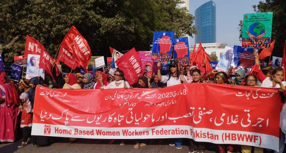 Frauen gehen protestierend einer Straße entlang mit Fahnen und Banner