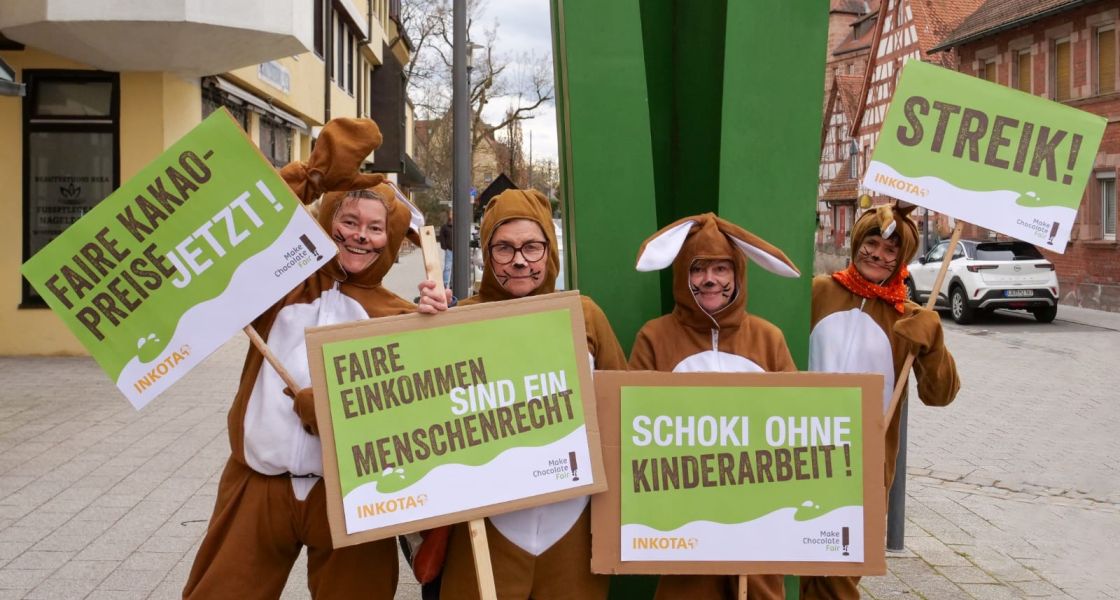 Vier Frauen in Osterhasenkostümen halten Protestschilder hoch