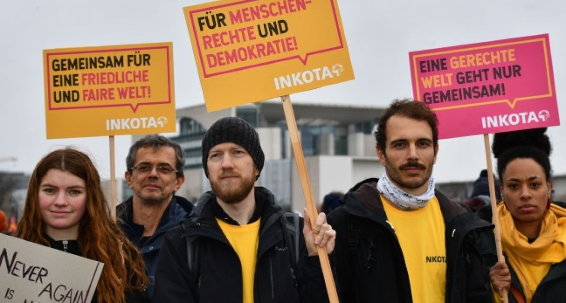 Gruppe von Menschen hält Protestschilder in die Höhe