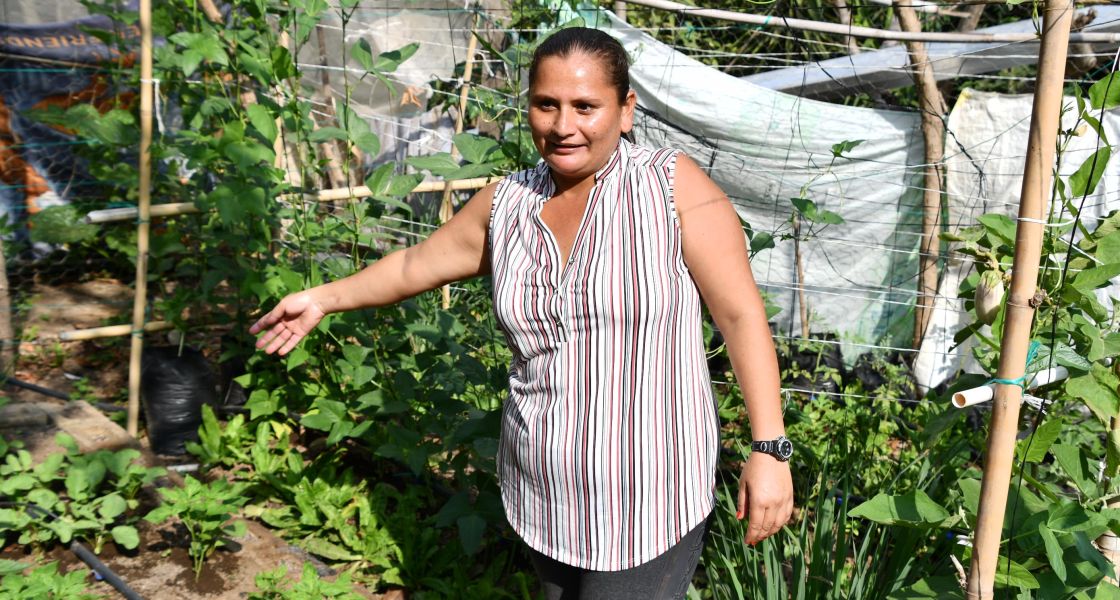 Frau zeigt auf ihren grünen Garten