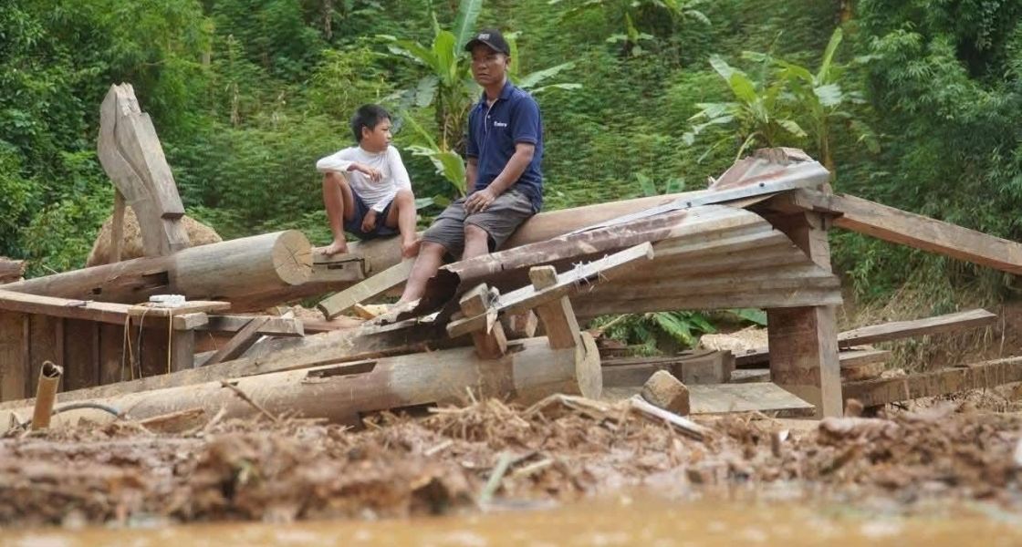Ein Junge und ein Mann sitzen auf einem zerstörten Haus