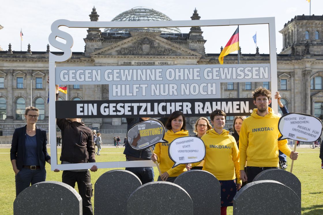 Eine Gruppe Mitarbeitende von Inkota stehen mit Protestschildern vor dem Reichstag in Berlin