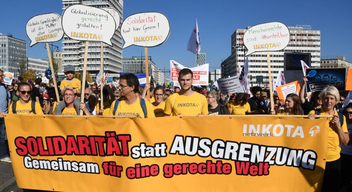 eine Menschenmenge mit einem großen Banner tragend und Protestschildern