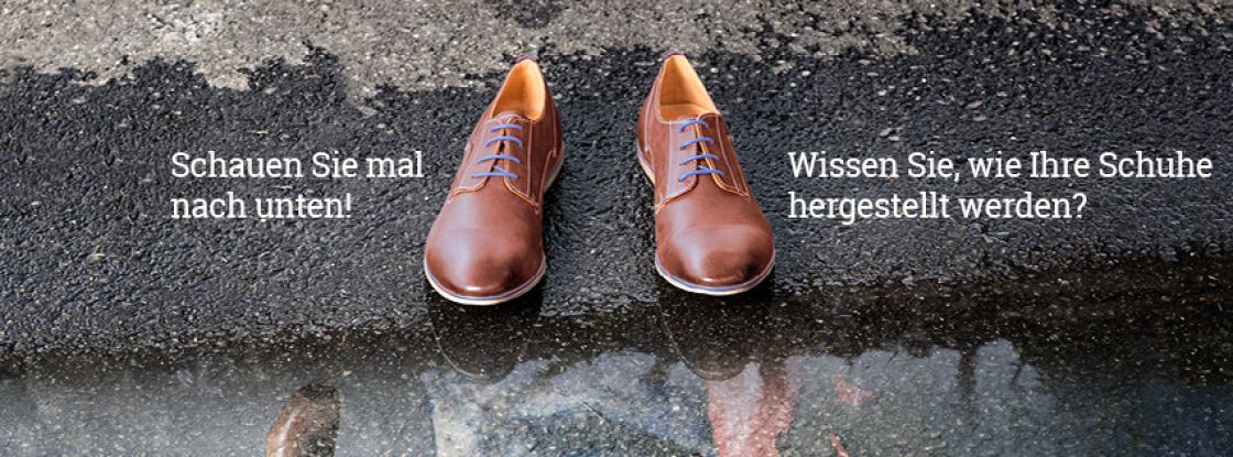 Ein Paar braune Herrenschuhe stehen auf dem Asphalt vor einer Pfütze