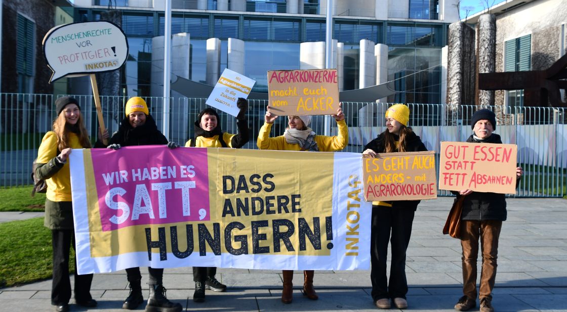 EIn Gruppe von Menschen vor dem Kanzleramt hält ein Banner mit der Aufschrift Wir haben es satt, dass andere hungern!