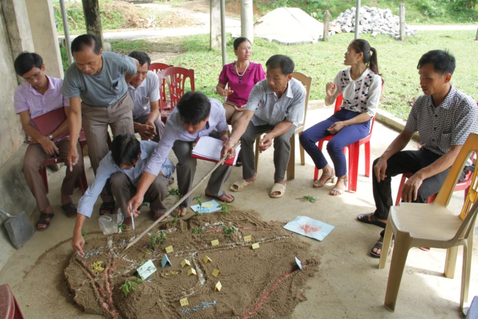 Mehrere Menschen betrachten ein Miniaturplan ihres Dorfes