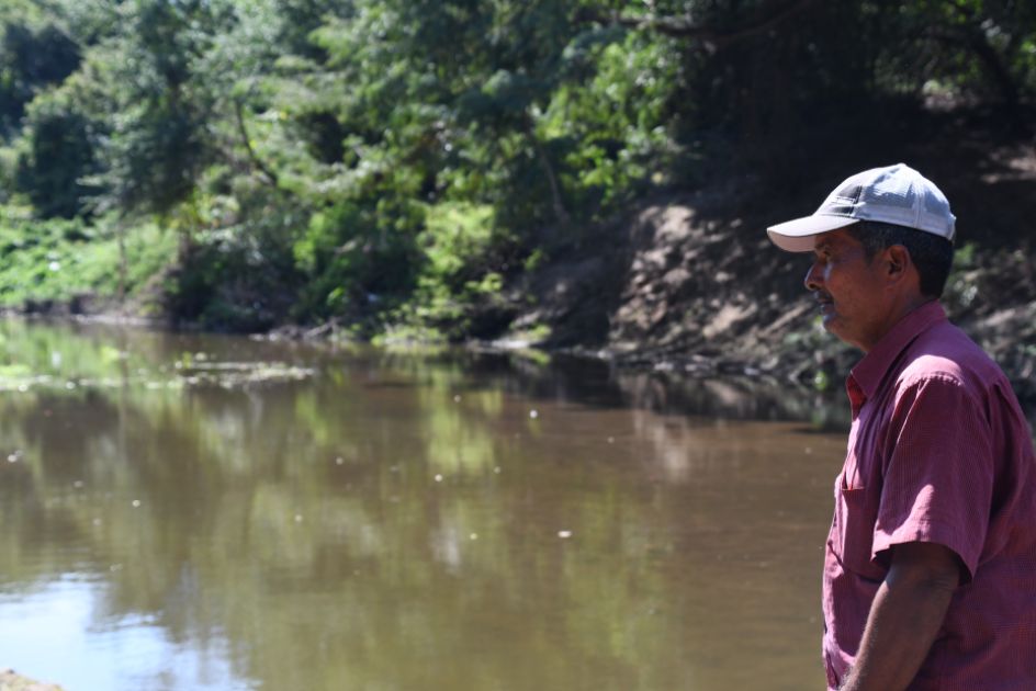 Ein Mann mit Käppi steht am Flußufer