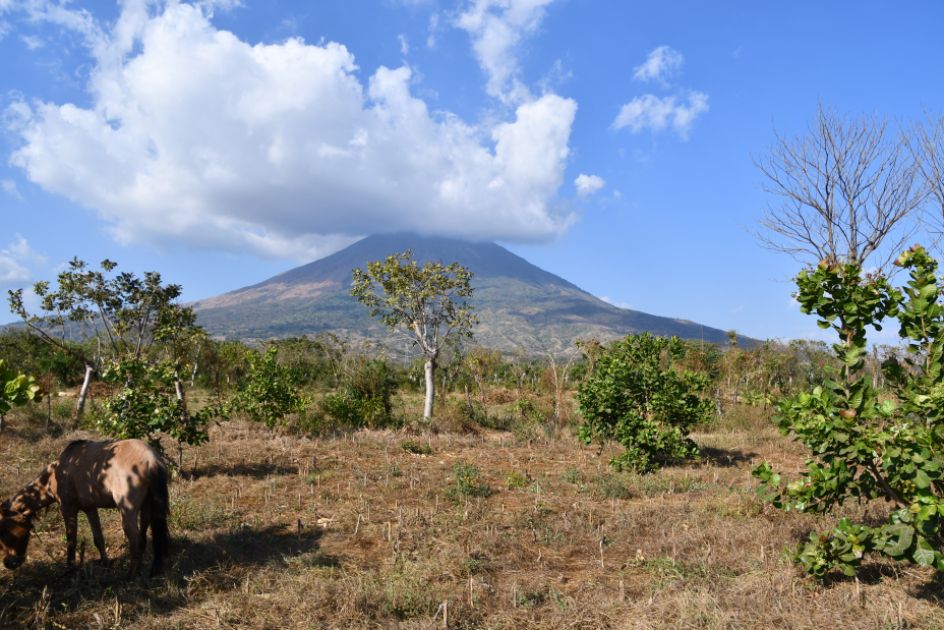 Ein Vulkan aus weiter Ferne. Am Gipfel hängt eine Wolke fest.