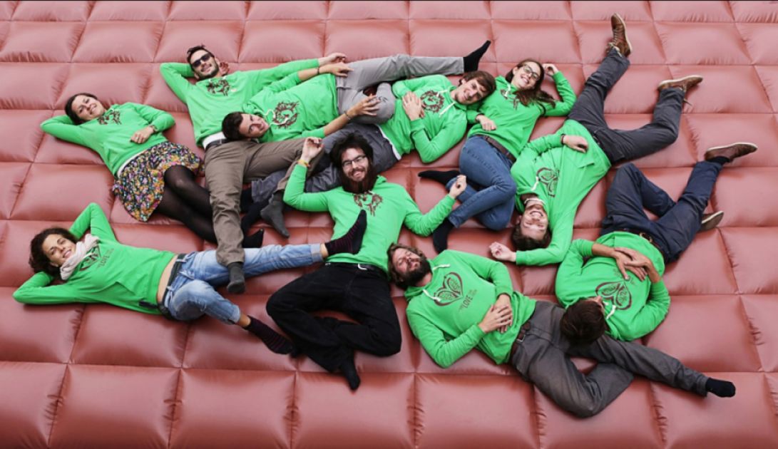 Mehrere Menschen mit günen Hoodies liegen auf einer braunen aufblasbaren Matte