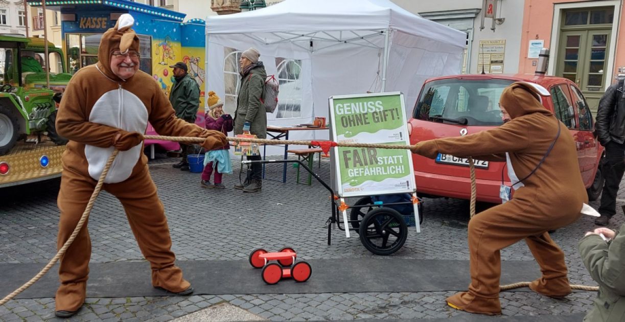 Zwei Personen in Osterhasenkostümen ziehen am Seil auf einem Marktplatz