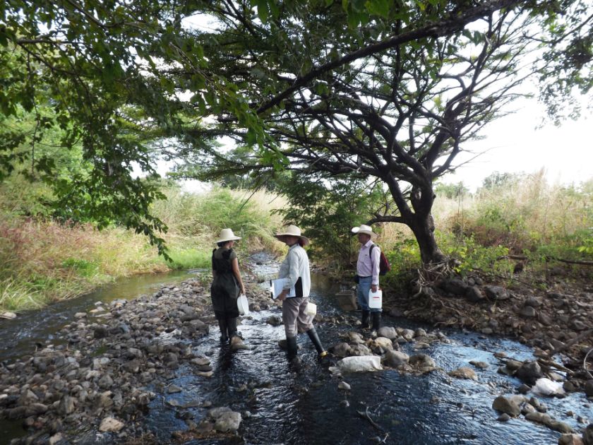 3 Personen mit weißen Hüten stehen in einem Flussbett