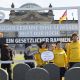 Eine Gruppe Mitarbeitende von Inkota stehen mit Protestschildern vor dem Reichstag in Berlin