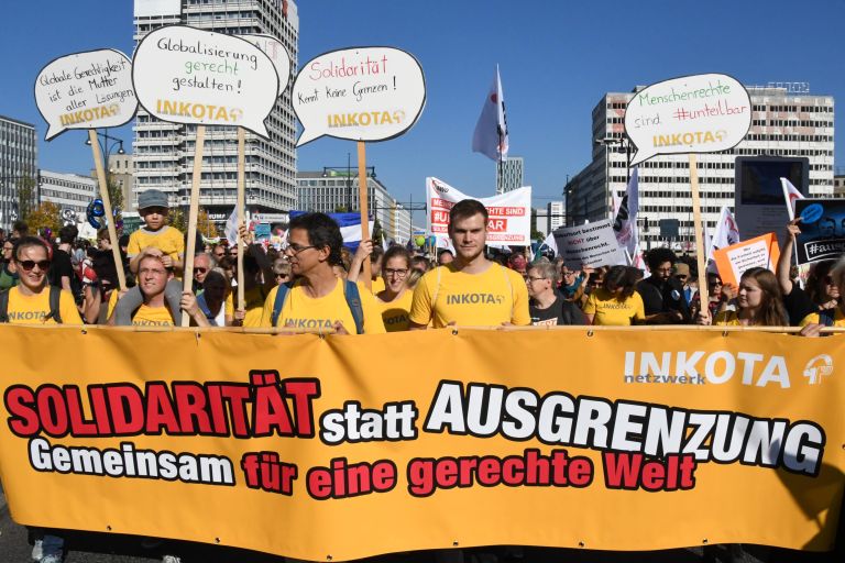 eine Menschenmenge mit einem großen Banner tragend und Protestschildern