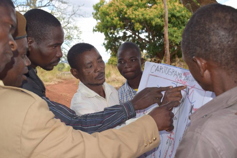 Gruppe Männer zeigen mit den Händen auf eine Karte