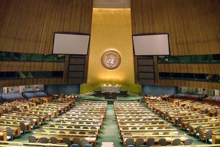 Ein großer Saal mmit vielen Sitzplätzen und in vorne mittig eine breite Wand goldfraben angemalt