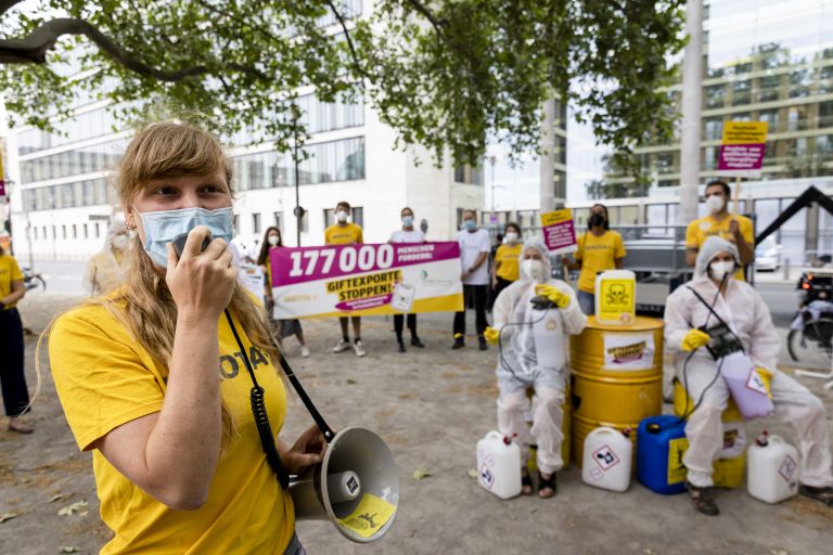 eine Frau mit Mundschutz spricht in ein Megafon
