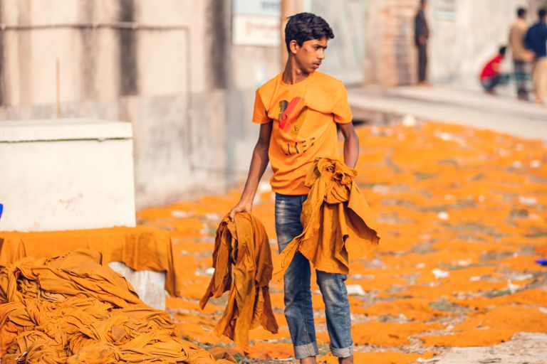 Ein Mann steht vor einem Haufen gegerbtes Leder und er hält ein paar Lederteile in der Hand