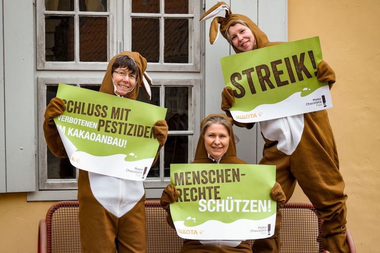 Drei Frauen in Osterhasenkostümen demonstrieren mit Plakaten