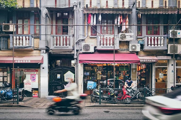 Eine Person, die mit einem Motorrad eine Straße neben hohen Gebäuden entlang fährt