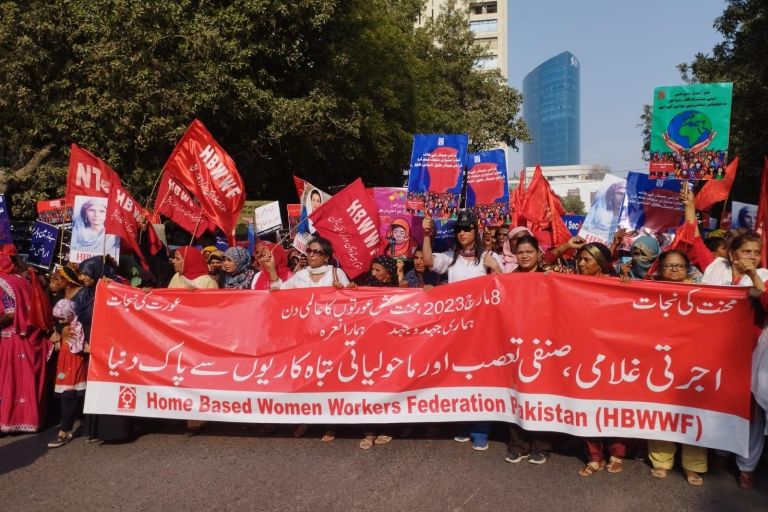 Frauen gehen protestierend einer Straße entlang mit Fahnen und Banner