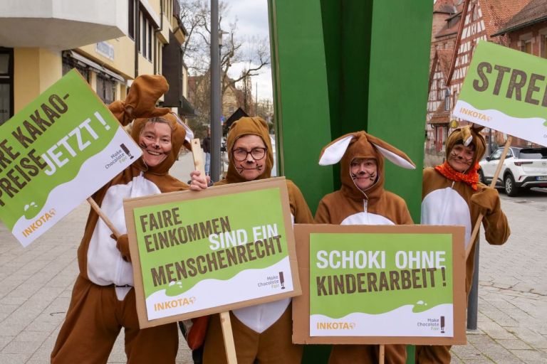 Vier Frauen in Osterhasenkostümen halten Protestschilder hoch