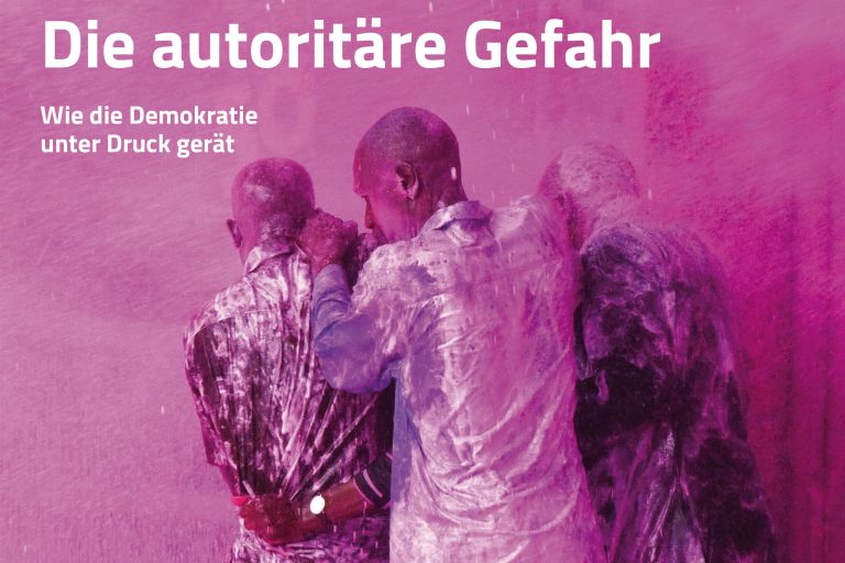 Drei Männer halten sich gegenseitig fest und schützen sich vor Rosa Partikelchen in der Luft