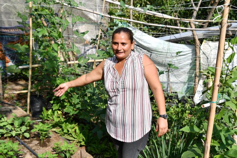 Frau zeigt auf ihren grünen Garten